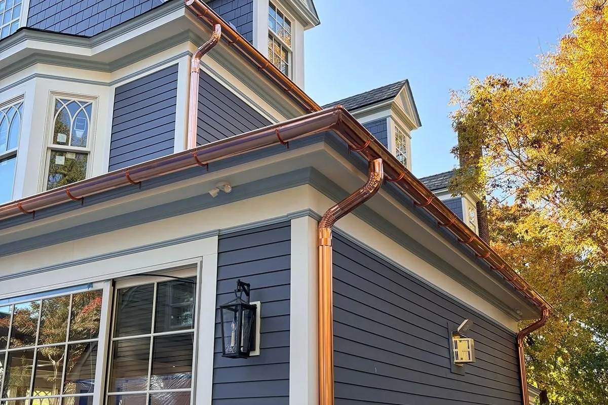 Copper half-round gutters and round copper downspouts on a two-story home
